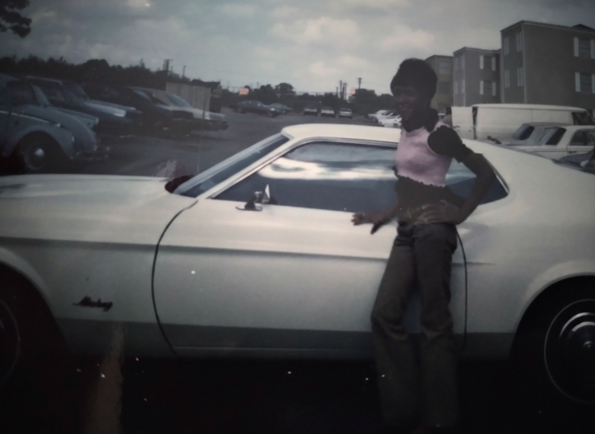 Knighton family member posing with a vintage Mustang